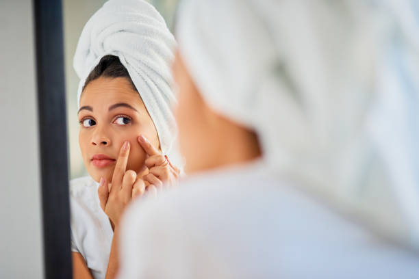 Jeune femme qui examine sa peau dans un miroir