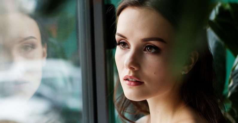 Jeune femme brune qui regarde par la fenêtre